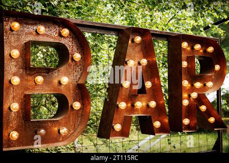 Bar signboard. Inscription from large metal letters decorated with glowing light bulbs Stock Photo