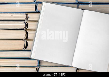 An open book with blank pages, a diary on a stack of shabby books standing on their ends. Top view with copy space Stock Photo