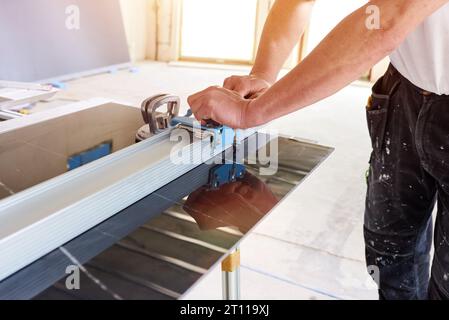 Construction worker cutting ceramic tiles using ceramic cutter Stock Photo