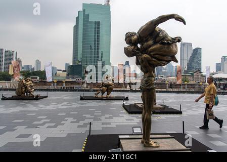 A visitor walks past sculptures created by Chinese artist Xu Hongfei outside Iconsiam the shopping mall. An exhibition 'Xu Hongfei Sculpture World Tour Exhibition - Thailand: Love in Siam' was held at Iconsiam the shopping mall displayed sculptures created by Chinese artist Xu Hongfei presenting happiness, humor and relationship between Thailand and China. Stock Photo