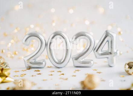 Greeting card - happy new year with numbers 2024, decoration lights and Christmas balls on white background. Minimal holiday concept. Front view. Copy Stock Photo