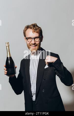 Celebration of the new year. Red-haired young man with a bottle of champagne isolated on a white background. Stock Photo