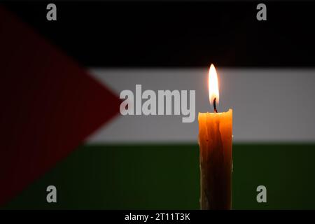 Mourning in country palestine, gaza strip. A burning candle on the background of the palestinian flag. Victims of cataclysm or war concept. National m Stock Photo