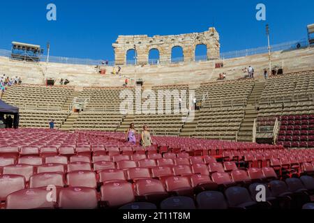 Visitors walking through rows of red seats in interior of the Arena di Verona, a well-preserved ancient Roman amphitheater located in Verona, Italy Stock Photo