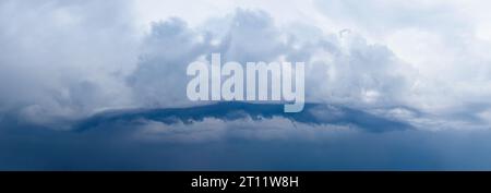 Cyclone thundercloud panorama of interesting shape. The sky before the rain. Dark Clouds. Huge black clouds on sunset. cloudy dark sky. Background of Stock Photo