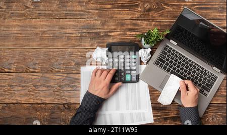 Male hand holding a check and using a calculator when filling out an individual tax return, close. Tax calculation, account, income and expense analys Stock Photo