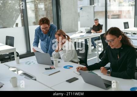 Business colleagues working together on project while sitting in office on colleagues background Stock Photo
