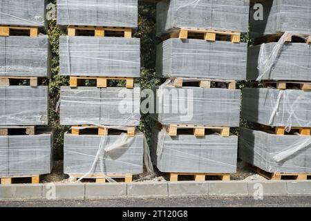 Pallets with stacked gray paving slabs selective focus Stack of paving slabs in warehouse road repair or finished tile sale space for text Stock Photo