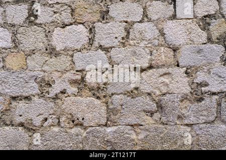 An old cobblestone sidewalk with grass and moss growing through it. View from above. Stock Photo