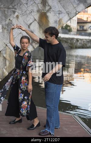 YOUNG COUPLE DANCING AT SUNSET ON THE RIVER BANK Stock Photo