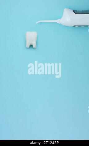 Irrigator near tooth model on blue background, professional clean teeth, teeth will good healthy. Dentist tools. Teethcare, dental health concept. Mea Stock Photo