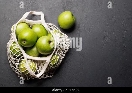 Mesh bag with fresh green apples on stone table. Flat lay with copy space Stock Photo