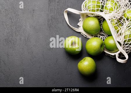 Mesh bag with fresh green apples on stone table. Flat lay with copy space Stock Photo
