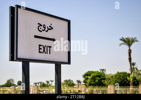 Luxor, Egypt - October 08 2021: A pointer to the exit in English and Arabic on a blue sky background near the temple of Karnak. Close-up. Stock Photo