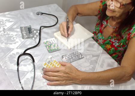 Senior woman checking her medications and taking notes Stock Photo