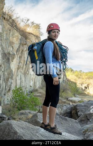 Portrait of female climber looking at camera at foot of rocky mountain. Extreme outdoor sport. Stock Photo