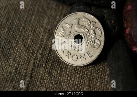 1 Krone Harald V. Norwegian coin and stones on natural linen fabric. Business and finance. Stock Photo