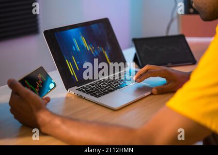 Cropped photo of an unrecognizable trader analyzing the data of investment on crypto using laptop and tablet at home Stock Photo