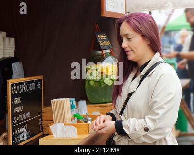 Pretty young woman standing at a coffee stall reading her coffee menu at the Farmers Street Food Market in Prague Stock Photo