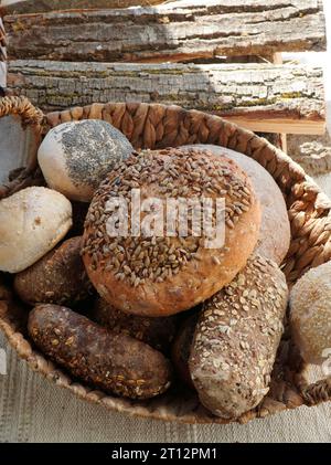 Variety of traditional breads and buns with seeds and whole grains in basket at bakery Stock Photo