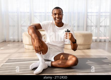 Positive millennial sporty black man drinking water Stock Photo