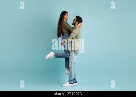 Loving handsome middle eastern guy lifting up his girlfriend Stock Photo