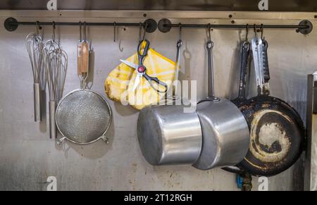 Different cooking utensils hung up on a metal wall in the kitchen of a pizza shop in Monroeville, Pennsylvania, USA Stock Photo
