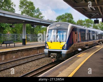 A local commuter train arrives at a deserted platform at Lanyon Place Station in Belfast, Northern Ireland, UK. Taken on a sunny day in summer. Stock Photo