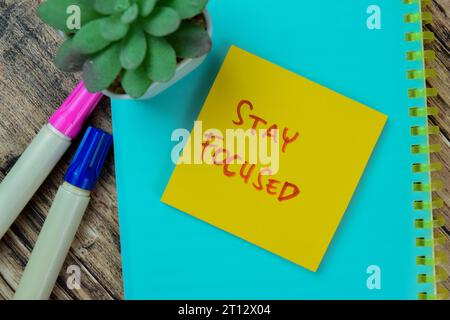 Concept of Stay Focused write on sticky notes isolated on Wooden Table. Stock Photo