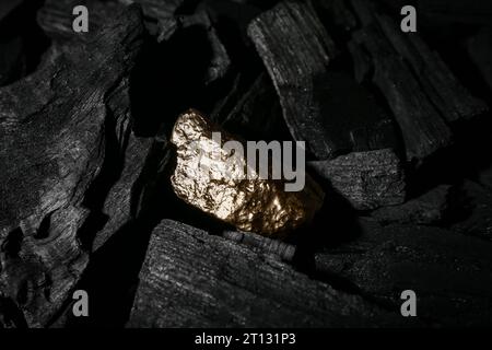 Golden nugget on black charcoal Stock Photo