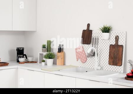 White kitchen counters with cutting boards, pegboard, sink and utensils Stock Photo