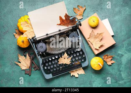 Vintage typewriter, pumpkins, keys, book and autumn leaves on green background Stock Photo