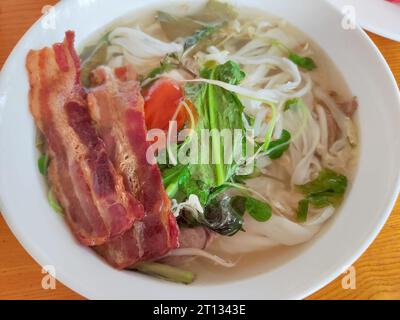bacon with green vegetables on the rice noodles in the soup for eating Stock Photo