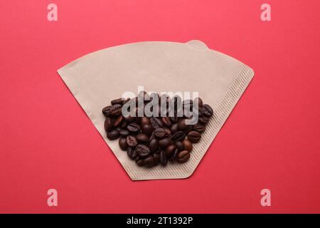 Paper coffee filter and beans on red background, top view Stock Photo