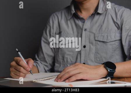 hand holding pen with writing or planning journal on note book in office Stock Photo
