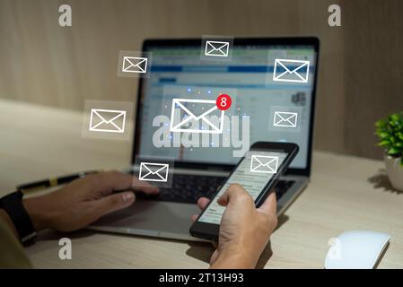 Businessman using laptop and mobile smartphone with email notification alert on virtual screen. Stock Photo