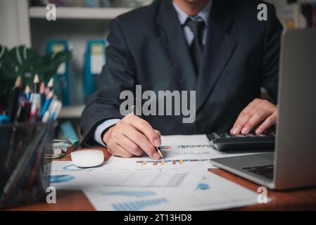 businessman working accountant document graph and chart on desk using calculator for calculate finance report in office. Stock Photo