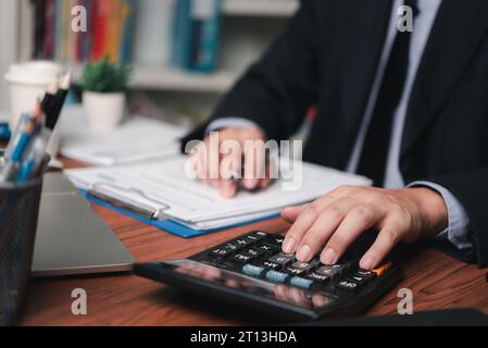 businessman working accountant document graph and chart on desk using calculator for calculate finance report in office. Stock Photo