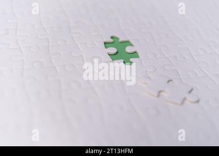 Puzzle pieces on green background.white jigsaw puzzle pieces copy space for text, top view. Stock Photo