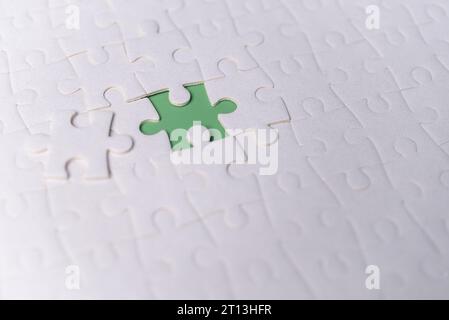Puzzle pieces on green background.white jigsaw puzzle pieces copy space for text, top view. Stock Photo