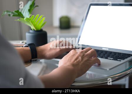 man using and typing on laptop computer mockup with blank screen. Stock Photo