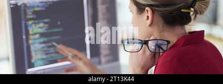 Female programmer checks code looking at screen of computer Stock Photo