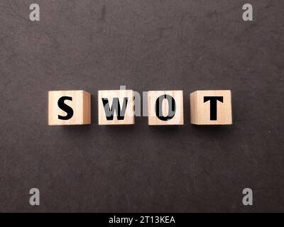 Top view wooden cube with the word SWOT on black background. Stock Photo