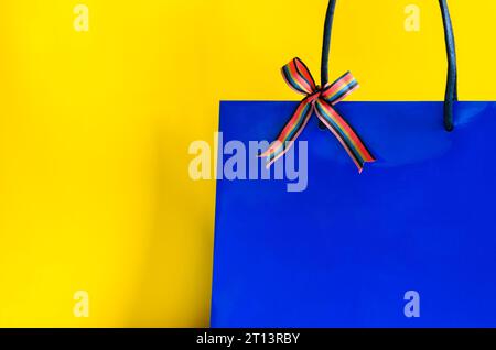 Blue shopping paper bag with ribbon on yellow background for Black Friday shopping sale concept. Stock Photo