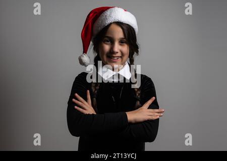 Portrait of little girl with Wednesday Addams costume. Wednesday girl with a Santa hat Stock Photo