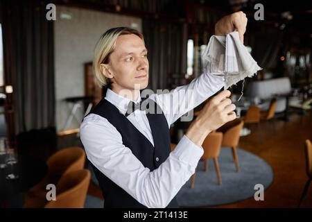 Waist up portrait of classic server with bowtie polishing glasses in luxury restaurant, copy space Stock Photo