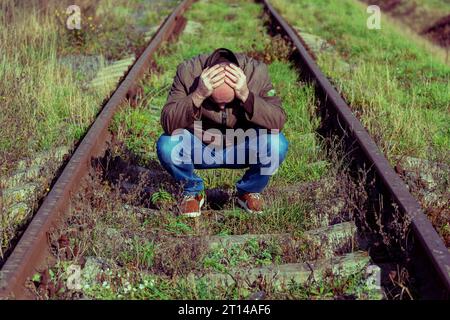 The thoughtful man sits on rails. The upset person in a stress.  Concept stress, failure of life, problem. Sad male Stock Photo