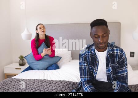 Sad diverse couple sitting on bed arguing at home Stock Photo