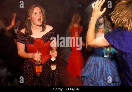 Sloane Rangers 1990s UK, disco dancing together. With two bottle of pink champagne in hand and a complexion and dress to match, a student Sloane Ranger gives it all she’s got on the disco dance floor at the Royal Agricultural College annual end of year summer May Ball. Cirencester Royal Agricultural College, Cirencester Gloucestershire, England, May 1995.  HOMER SYKES Stock Photo