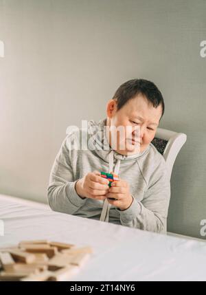 Focused Learning: Elderly Woman with Down Syndrome Engaged in Educational Board Games Stock Photo